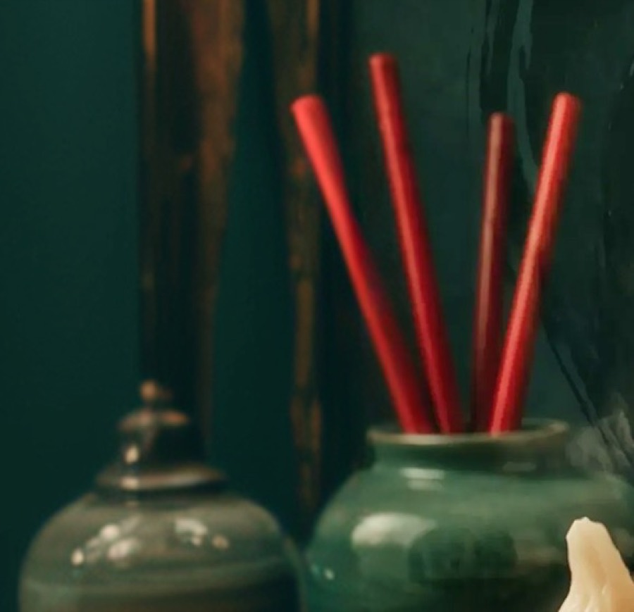 Red chopsticks standing in a green ceramic jar