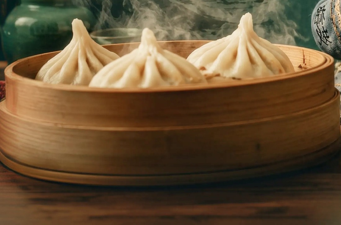 Three soup dumplings steaming in a bamboo basket